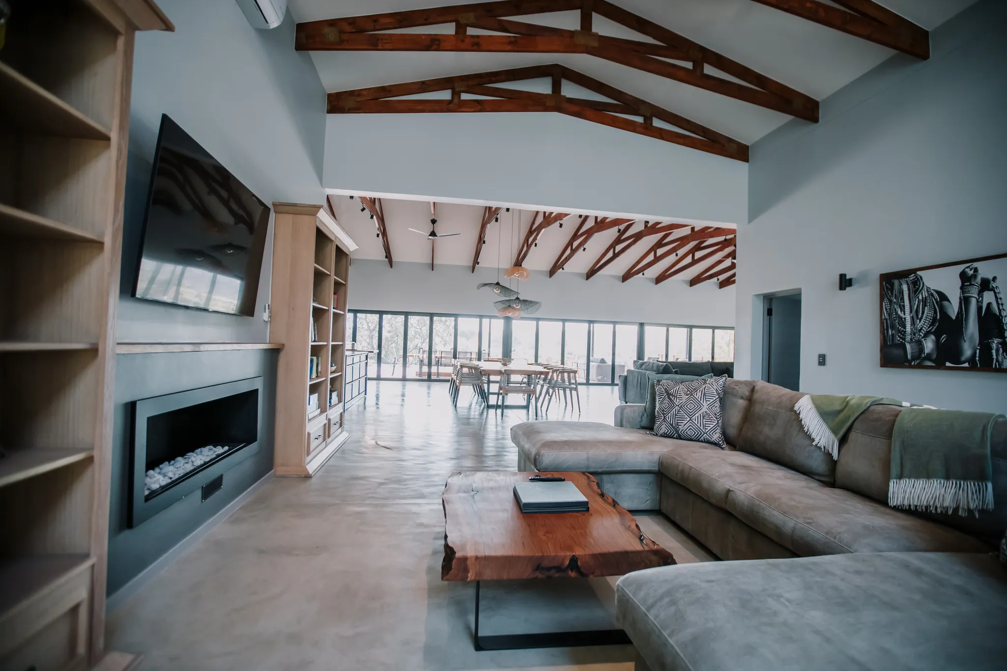 Entertainment room with large windows, a modern TV, fireplace and a couch.