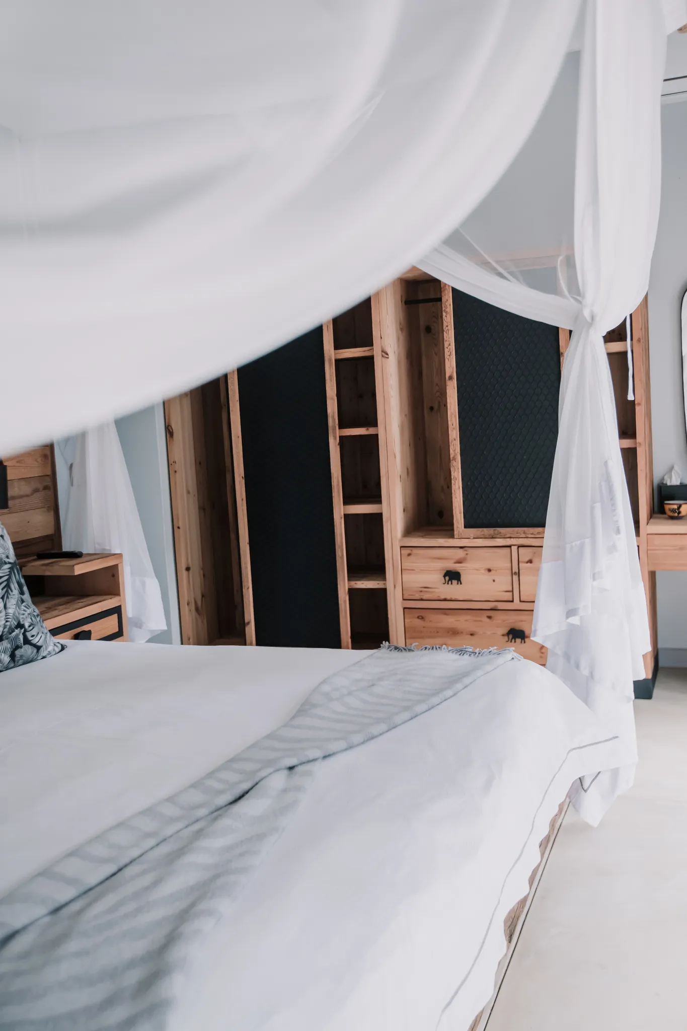 A white canopy bed with a wooden cupboard in the background.